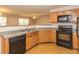 Well-lit kitchen featuring light wood cabinets, grey countertops, and black appliances at 5171 Hanover St, Atlanta, GA 30349