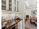 Wet bar area featuring dark stone countertops, glass shelving, and decorative tile backsplash at 1811 Paces Ferry Se Ct, Smyrna, GA 30080