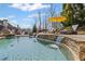 Stunning pool area featuring stone accents, cascading waterfalls, and lounge chairs under a yellow umbrella at 3323 Acorn Falls Dr, Marietta, GA 30062