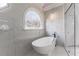 Luxurious bathroom boasts modern tub, white marble-style tile, and arched window at 490 Birkdale Dr, Fayetteville, GA 30215