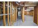 Unfinished basement with exposed wood beams, plumbing, and a partially finished wall with a door at 11385 Donnington Dr, Duluth, GA 30097
