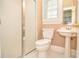 Bathroom featuring a toilet, shower, pedestal sink, and a bright window with natural light at 11385 Donnington Dr, Duluth, GA 30097