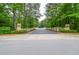 A gated community entrance with mature trees lining the private drive at 11385 Donnington Dr, Duluth, GA 30097