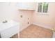 Laundry room featuring a utility sink, white cabinets, and tile flooring, with a bright window at 11385 Donnington Dr, Duluth, GA 30097