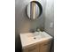 Well-lit bathroom featuring a round mirror and clean white countertop basin at 23 Poplar St, Porterdale, GA 30014