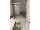 Modern bathroom features tiled shower/tub with sliding glass door, and neutral tiled flooring at 323 Concord St, Alpharetta, GA 30009