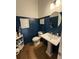 Stylish half bathroom with blue walls, pedestal sink, and hardwood floors at 323 Concord St, Alpharetta, GA 30009