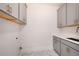 Laundry room features gray cabinets with modern hardware, quartz countertops, and stylish marble flooring at 115 Alcovy Ter, Alpharetta, GA 30009