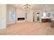 Open-concept living room with modern chandelier, fireplace, and light wood floors leading to the kitchen at 115 Alcovy Ter, Alpharetta, GA 30009