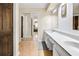 Well-lit bathroom featuring wood floors, a white double sink vanity, and mirrored closet doors at 4203 Deerbrook Sw Way, Lilburn, GA 30047