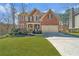 Charming two-story red brick home featuring a well-manicured lawn and an attached two-car garage at 1654 Summersweet Ln, Dacula, GA 30019