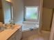 Bright bathroom featuring a bathtub with tile surround, plus separate shower and bright vanity at 704 Euel Dr, Mcdonough, GA 30252