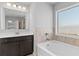 Elegant bathroom featuring a soaking tub, dark vanity, and a bright window at 7630 Rambling Vale, Cumming, GA 30028