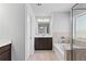 Modern bathroom with dark vanity, tiled flooring, a soaking tub, and glass-enclosed shower at 7630 Rambling Vale, Cumming, GA 30028