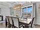 Bright dining area showcasing a wooden table, seating for eight, a modern light fixture, and large windows at 7630 Rambling Vale, Cumming, GA 30028
