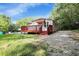 Charming home with a red deck, awning, and a gravel driveway surrounded by lush green trees at 5125 West St, Forest Park, GA 30297