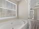 Relaxing bathroom featuring a soaking tub, hardwood floors, and natural light from the window at 195 Brighton Dr, Covington, GA 30016