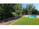 Fenced in-ground swimming pool bordered by trees and iron fence at 3416 Haddon Hall Ct, Buford, GA 30519