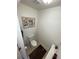 Small powder room with neutral paint and tile, a modern toilet, vanity, decorative art, and clean, minimalist design at 828 Cedar Stream Ct, Loganville, GA 30052