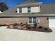Home exterior featuring garden beds, brick facade and manicured landscaping at 828 Cedar Stream Ct, Loganville, GA 30052