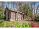 Charming log cabin exterior with a stone chimney surrounded by lush greenery and a wooded area at 1225 W Wesley Nw Rd, Atlanta, GA 30327