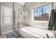 Bright bathroom with glass shower, soaking tub, and a window overlooking the backyard at 1370 Wheatfield Dr, Lawrenceville, GA 30043