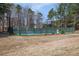 An enclosed tennis court is surrounded by tall trees, offering shade and privacy for community residents at 1370 Wheatfield Dr, Lawrenceville, GA 30043