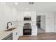 Well-lit kitchen with stainless appliances, white cabinets, and view of the living room fireplace at 489 Natasha Dr, Auburn, GA 30011