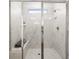 Close up of spacious shower with marble-like tile, a built-in bench, and a glass door at 1269 Pj East Rd, Covington, GA 30014