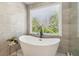 Modern bathroom with a sleek freestanding tub and light gray tiling at 7270 Sheffield Pl, Cumming, GA 30040