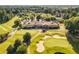 Aerial view of golf course and clubhouse featuring manicured greens and a covered veranda at 7270 Sheffield Pl, Cumming, GA 30040