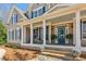 Inviting covered front porch with rocking chairs, columns, and a blue front door at 7270 Sheffield Pl, Cumming, GA 30040