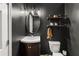 This half bath offers a dark color scheme, mirror, and industrial shelving above the toilet at 410 Wilkinson Se Dr, Atlanta, GA 30317