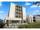 Modern condominium building with private balconies, seating area, and lush landscaping under a blue sky at 1421 Peachtree Ne St # 415, Atlanta, GA 30309