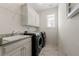 Bright laundry room with tile floors, modern washer and dryer, granite countertop, sink, and white cabinets at 1818 Cromwell Walk, Dunwoody, GA 30338