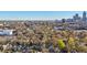 Aerial shot showcasing city skyline behind leafy neighborhood with a brown house nestled among green trees and rooftops at 313 5Th Ne St, Atlanta, GA 30308