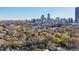Overhead view reveals city skyline, leafy neighborhood, and a brown home surrounded by trees, showcasing urban living at 313 5Th Ne St, Atlanta, GA 30308
