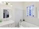 Bright bathroom featuring a tub with white tile surround and a stained-glass window at 313 5Th Ne St, Atlanta, GA 30308