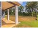 Covered back porch with columns, offering a serene view of the green backyard and surrounding trees at 246 Orwell Dr, Social Circle, GA 30025
