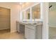 Bathroom with double sinks, granite countertop, and illuminated mirrors, leading to the walk-in closet at 246 Orwell Dr, Social Circle, GA 30025