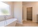 Luxurious bathroom with a freestanding soaking tub, walk-in shower, and tile flooring at 246 Orwell Dr, Social Circle, GA 30025