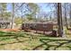 Backyard with a wooden deck attached to a brick house, surrounded by mature trees and a grassy area at 2780 Eastfield Se Rd, Smyrna, GA 30080