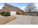 Home exterior featuring a two-car garage, American flag, and wide driveway with a pond in the background at 348 Lauren Ln, Woodstock, GA 30188