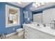 Charming bathroom with blue walls, a white vanity and cabinet, and a window overlooking nature at 587 Morgan Ct, Hampton, GA 30228