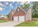 Side view of brick home featuring a two-car garage, a combination brick and vinyl exterior and fenced yard at 105 Kentwood Springs Dr, Hampton, GA 30228