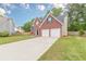 Well-maintained brick home showcasing a long driveway leading to a two-car garage and mature trees at 105 Kentwood Springs Dr, Hampton, GA 30228
