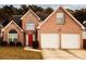 Charming two-story brick home with a well-manicured lawn, attached two car garage and a bright red front door at 11532 Ethan Ct, Hampton, GA 30228