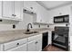This kitchen features white cabinetry, granite countertops, and black appliances at 116 Tallapoosa St, Temple, GA 30179