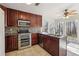 Modern kitchen with stainless steel appliances, wood cabinets, and a window overlooking the backyard at 1108 Gwens Sw Trl, Lilburn, GA 30047