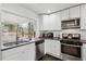 Well-lit kitchen featuring stainless steel appliances, white cabinets, and a large window with a backyard view at 2336 Mark Trl, Decatur, GA 30032